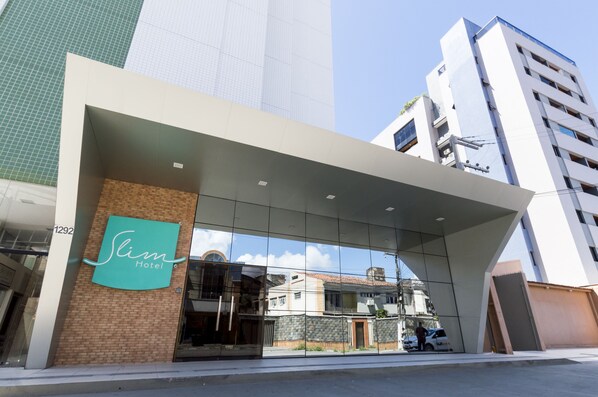 A hotel entrance with a modern design, large glass windows, and a prominent logo. - Slim Pajuçara by Tropicalis (Maceió)