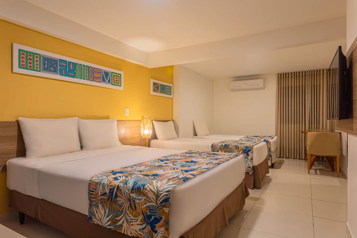A hotel room with two beds, a desk, and a TV.