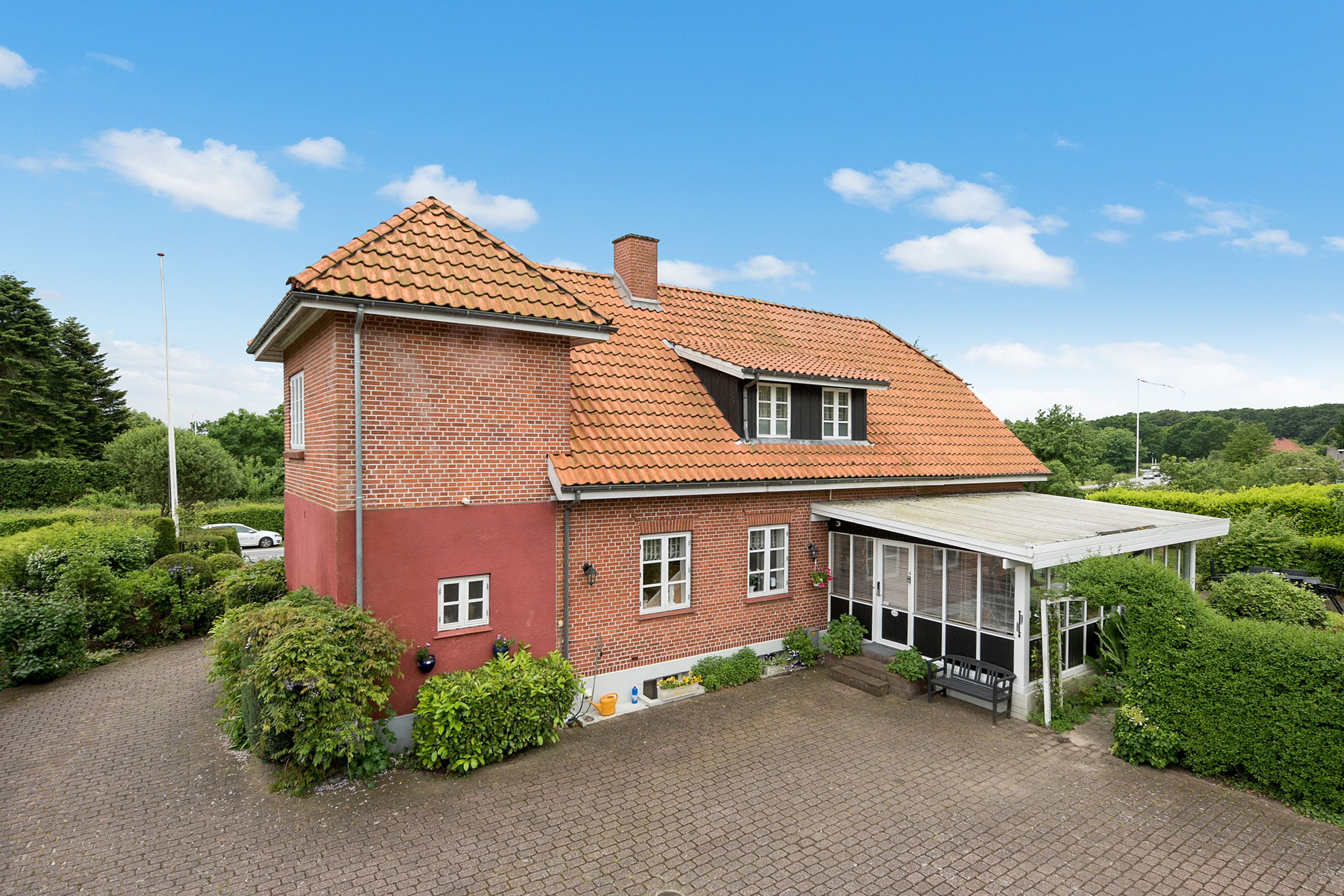 Une maison à deux étages avec une façade en briques rouges et un toit recouvert de tuiles.