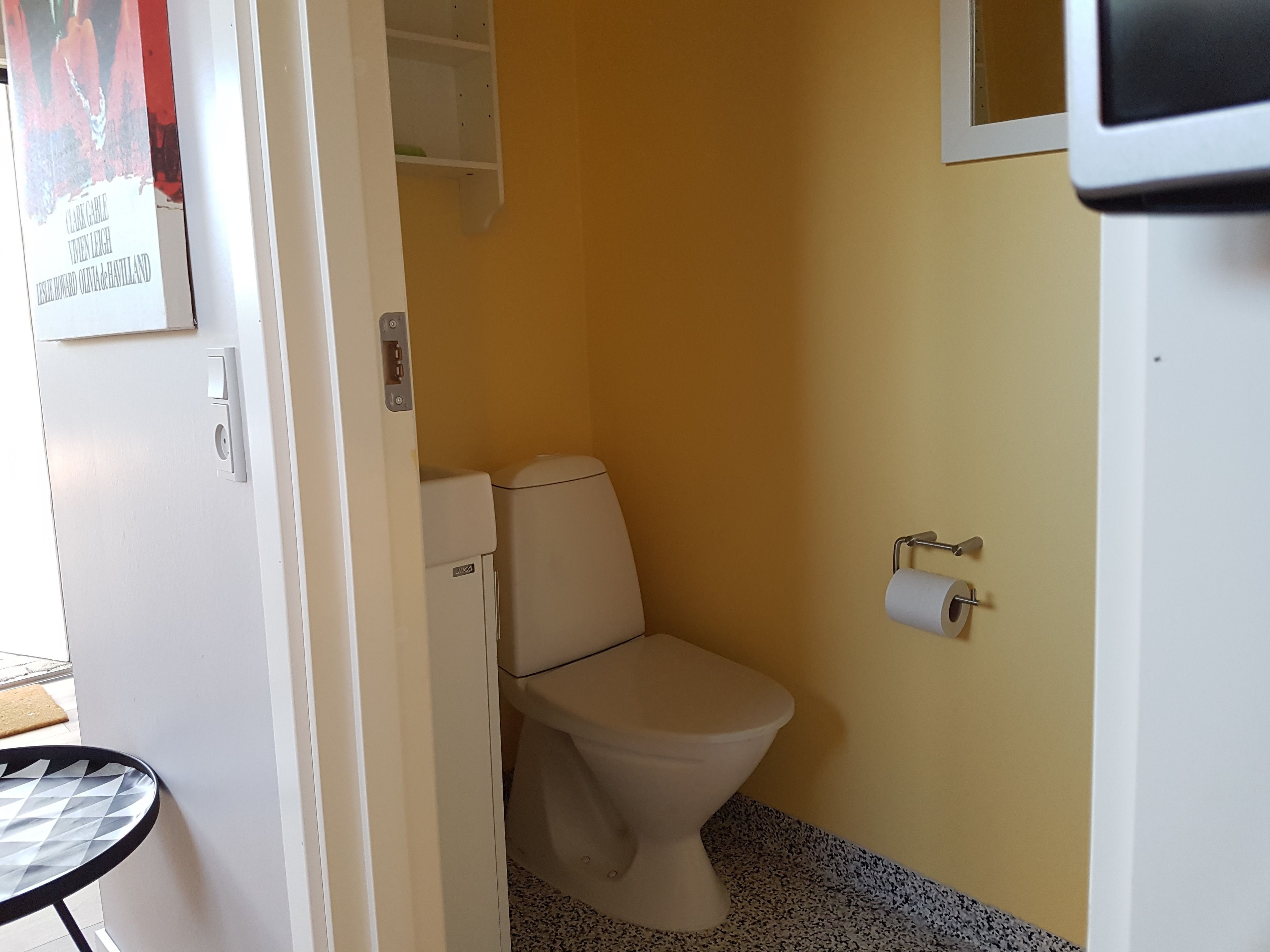 A small bathroom with a toilet, a paper towel dispenser, and a white door.
