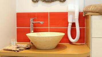 A bathroom with a beige sink, a chrome faucet, and red tiles.