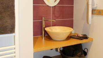 Un baño con tocador de madera, lavamanos color beige, espejo y perchero para toallas.
