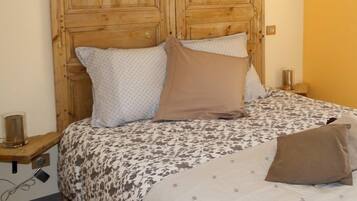 A bedroom with a wooden headboard, a patterned bedspread, and two bedside tables with lamps.