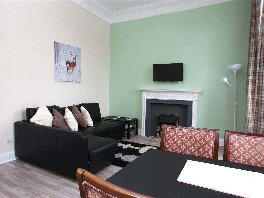 A living room with a sofa, chairs, a fireplace, and a television.