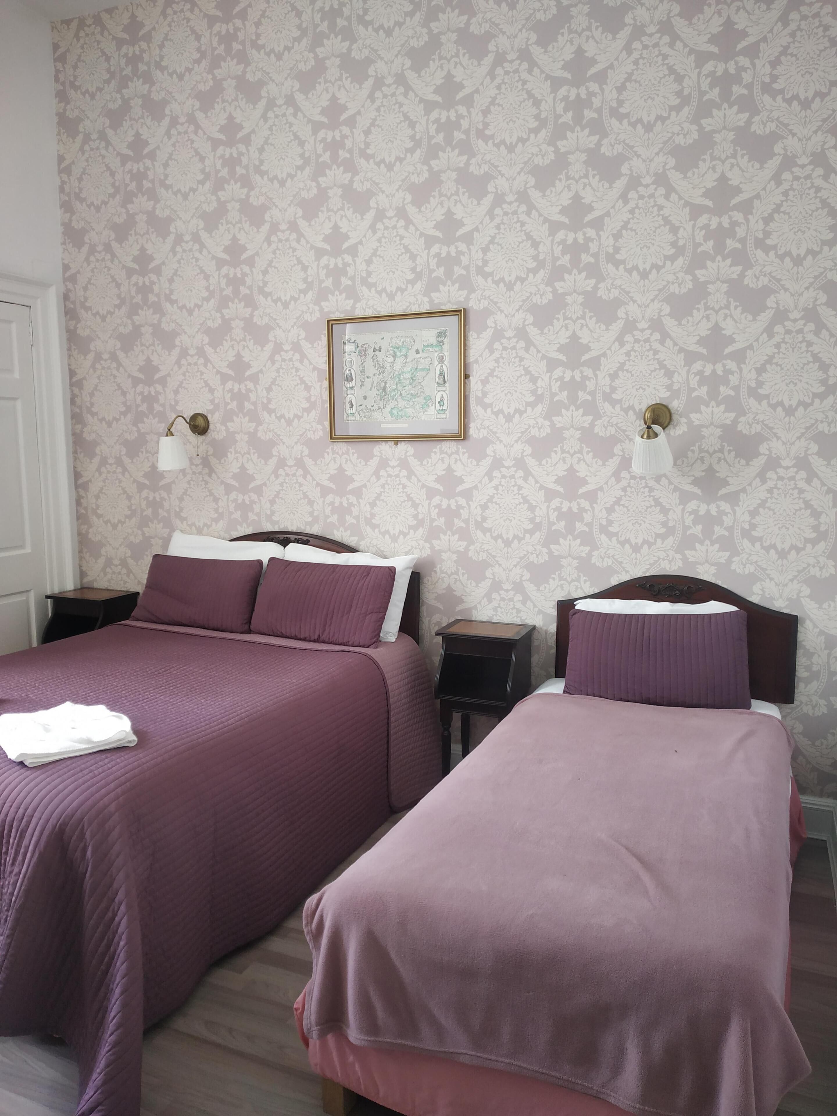Una camera d'albergo con due letti, una mappa incorniciata a parete e due comodini con lampade.