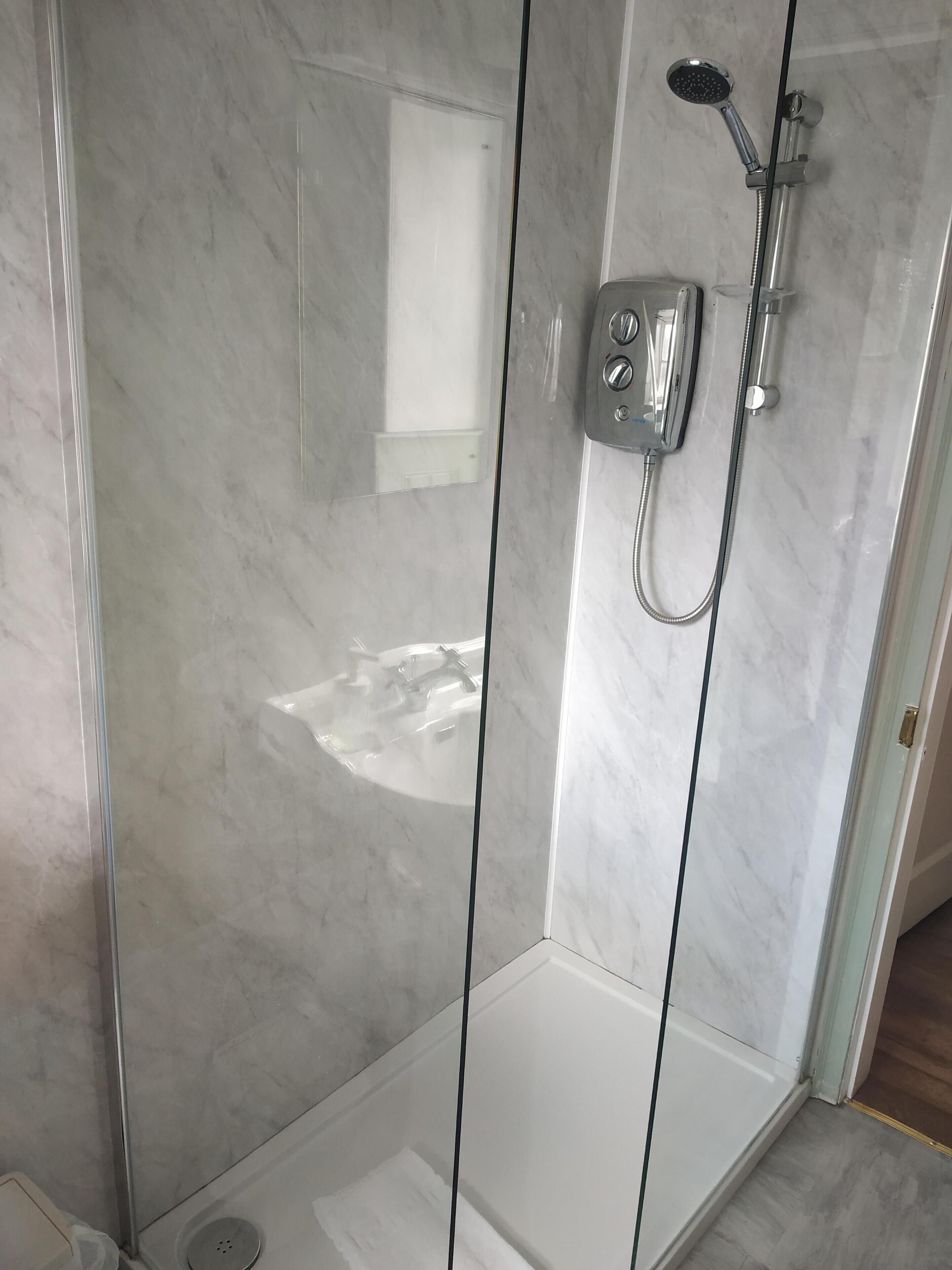 A modern bathroom with a glass shower enclosure, a built-in sink, and a toilet.