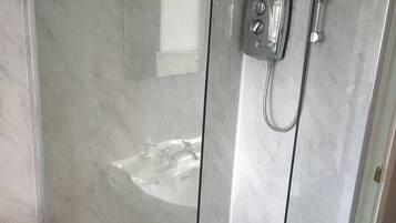 A modern bathroom with a glass shower enclosure, a built-in sink, and a toilet.