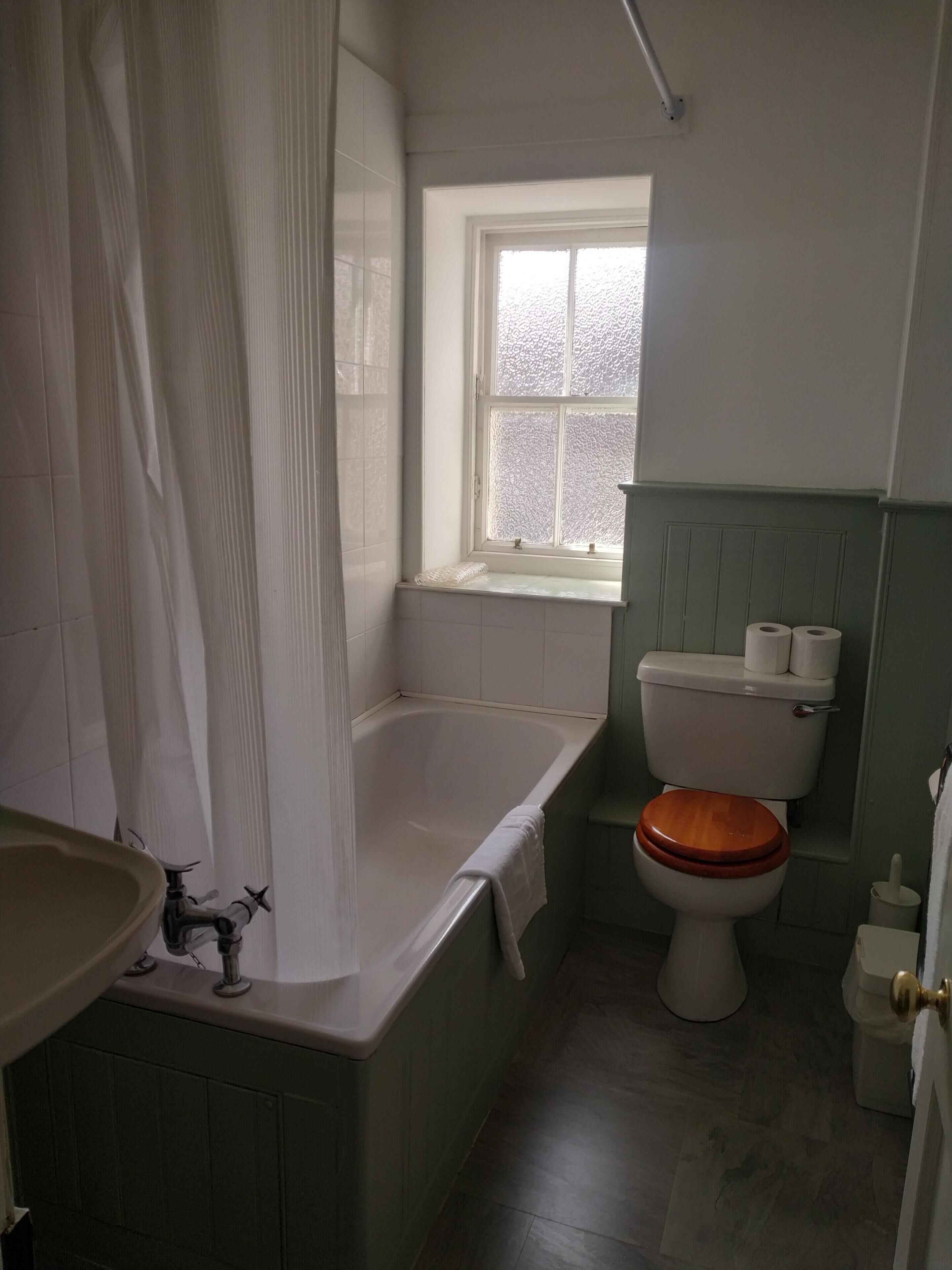 Een badkamer met een bad, toilet en wastafel.