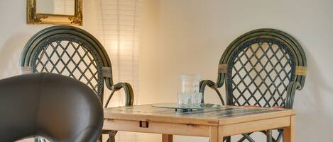 A dining area with a wooden table, two wicker chairs, a glass candle holder, and a tall floor lamp.