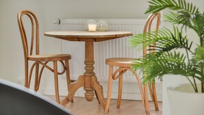 A round wooden table with two chairs, a lit candle, and a radiator in the background. - Bjerndrup Apartments (Aabenraa)