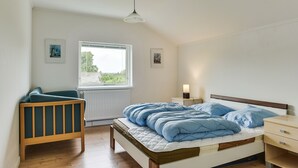 A bedroom with a bed, a nightstand, a chair, and a window. - Bjerndrup Apartments (Aabenraa)
