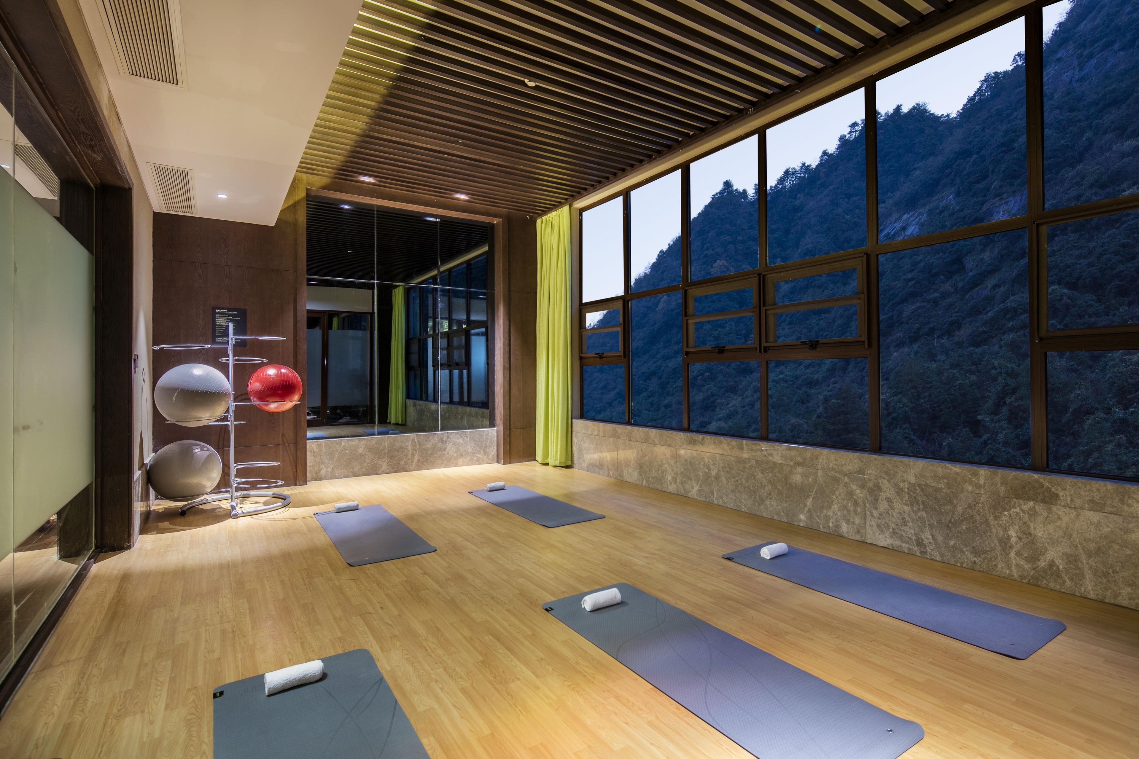 Un salón de yoga con piso de madera, pelotas de ejercicio y colchonetas.