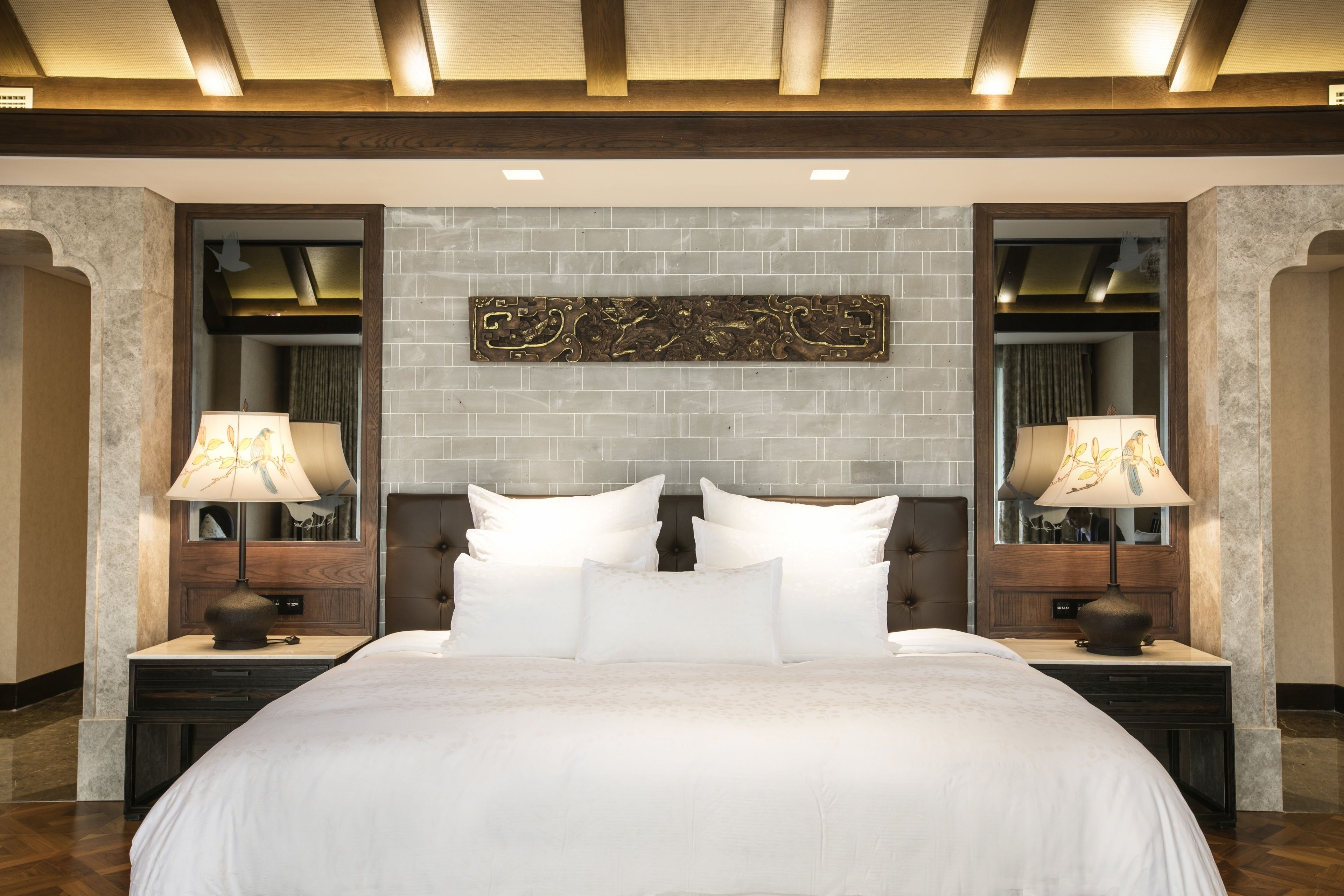 Un dormitorio ordenado con una cama grande, dos mesitas de noche y un adorno decorativo sobre la cama.