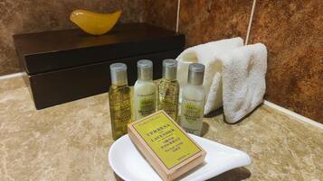 Una encimera de baño con un jabonero blanco, una pastilla de jabón amarilla y cuatro productos de lavanda Crabtree & Evelyn.