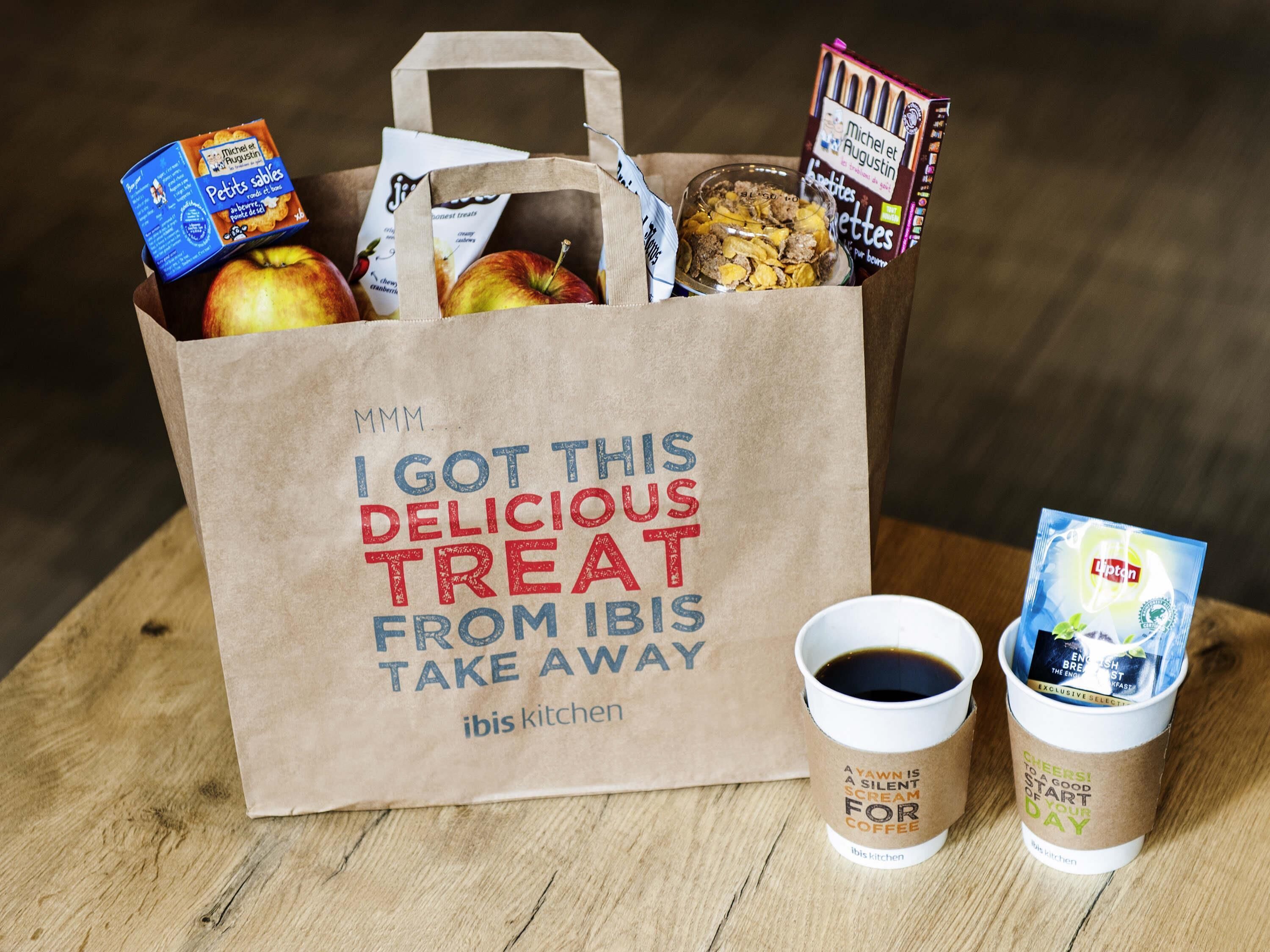 A paper bag with the text "I GOT THIS DELICIOUS TREAT FROM IBIS TAKE AWAY" and a cup of coffee with a label that says "A YAWN IS A SILENT SCREAM FOR COFFEE".