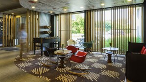 A modern interior with a foosball table, seating area, and large windows. - ibis De Haan (De Haan)