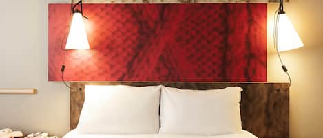 A neatly made bed with white linens, a wooden headboard, and two bedside tables with lamps.