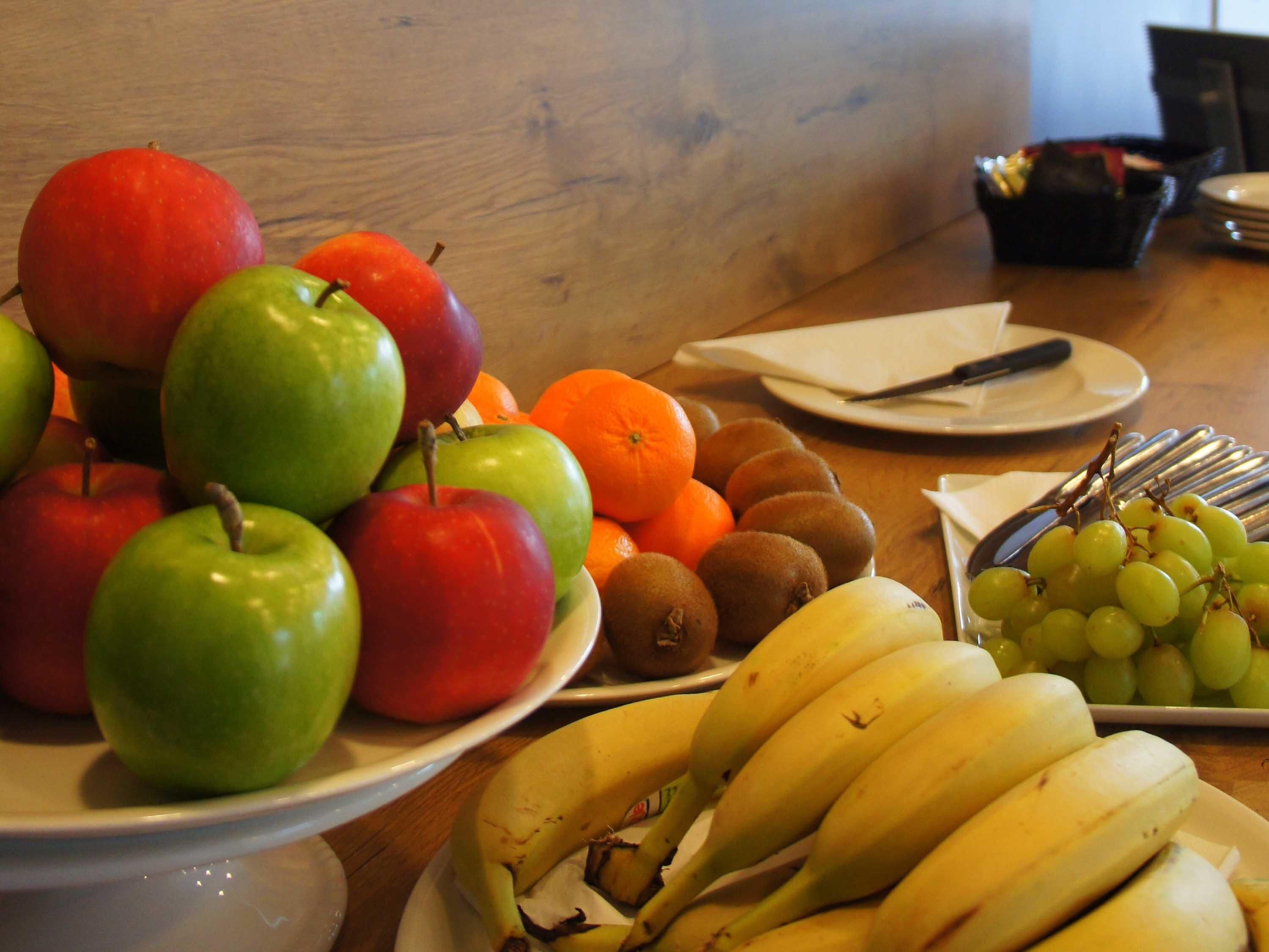 Una bandeja de frutas con manzanas, naranjas, kiwis, plátanos y uvas.