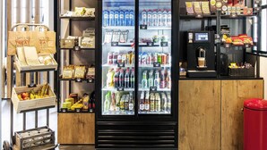A beverage refrigerator stocked with various drinks, a coffee machine, and shelves with snacks and condiments. - ibis De Haan (De Haan)