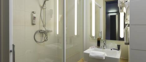 Un baño moderno con cabina de ducha de vidrio, tocador con lavamanos y espejo con iluminación integrada.