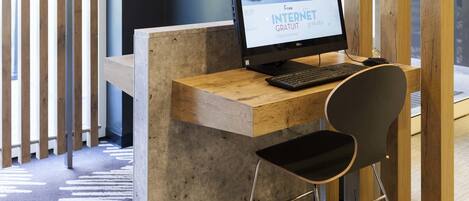 A reception desk with a computer, a chair, and a wooden partition.