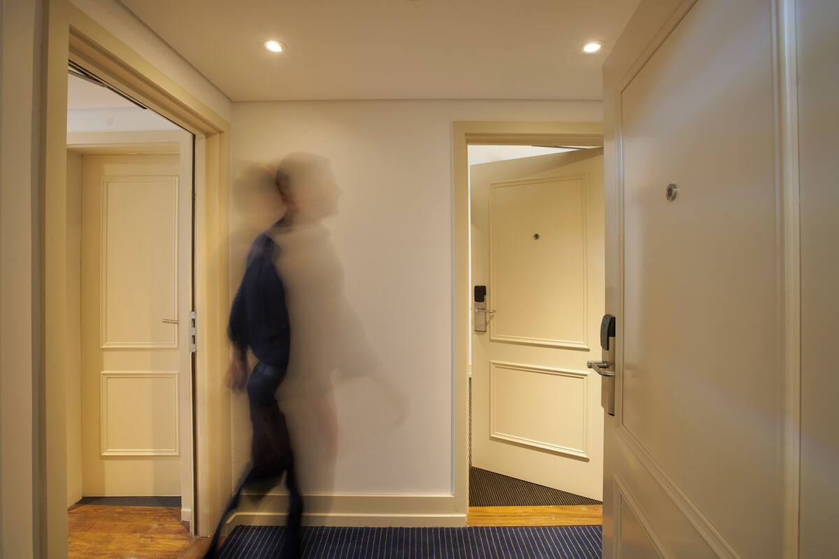 A hallway with double doors, a carpeted floor, and a ceiling with recessed lighting.