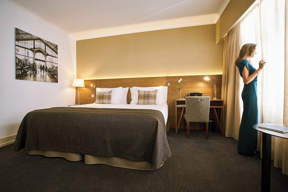 A hotel room with a large bed, a desk, and a chair.