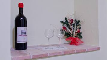 A bottle of rosso piceno wine on a shelf with two empty wine glasses and a small Christmas decoration.