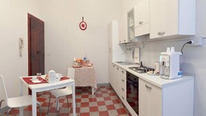 Cocina compacta con mesa de comedor, sillas, una mesita con alimentos y una cafetera.