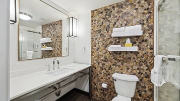 A modern bathroom with a white sink, a large mirror, a toilet, and a shower area.