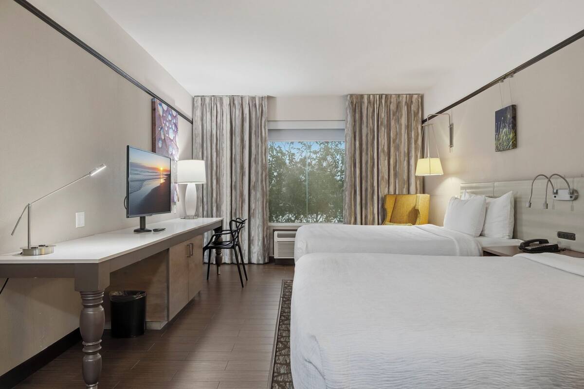 A hotel room with a bed, desk, chair, and a TV.