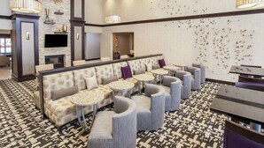 A modern lounge area with a sofa, round tables, and a fireplace. - Homewood Suites by Hilton Munster (Munster)