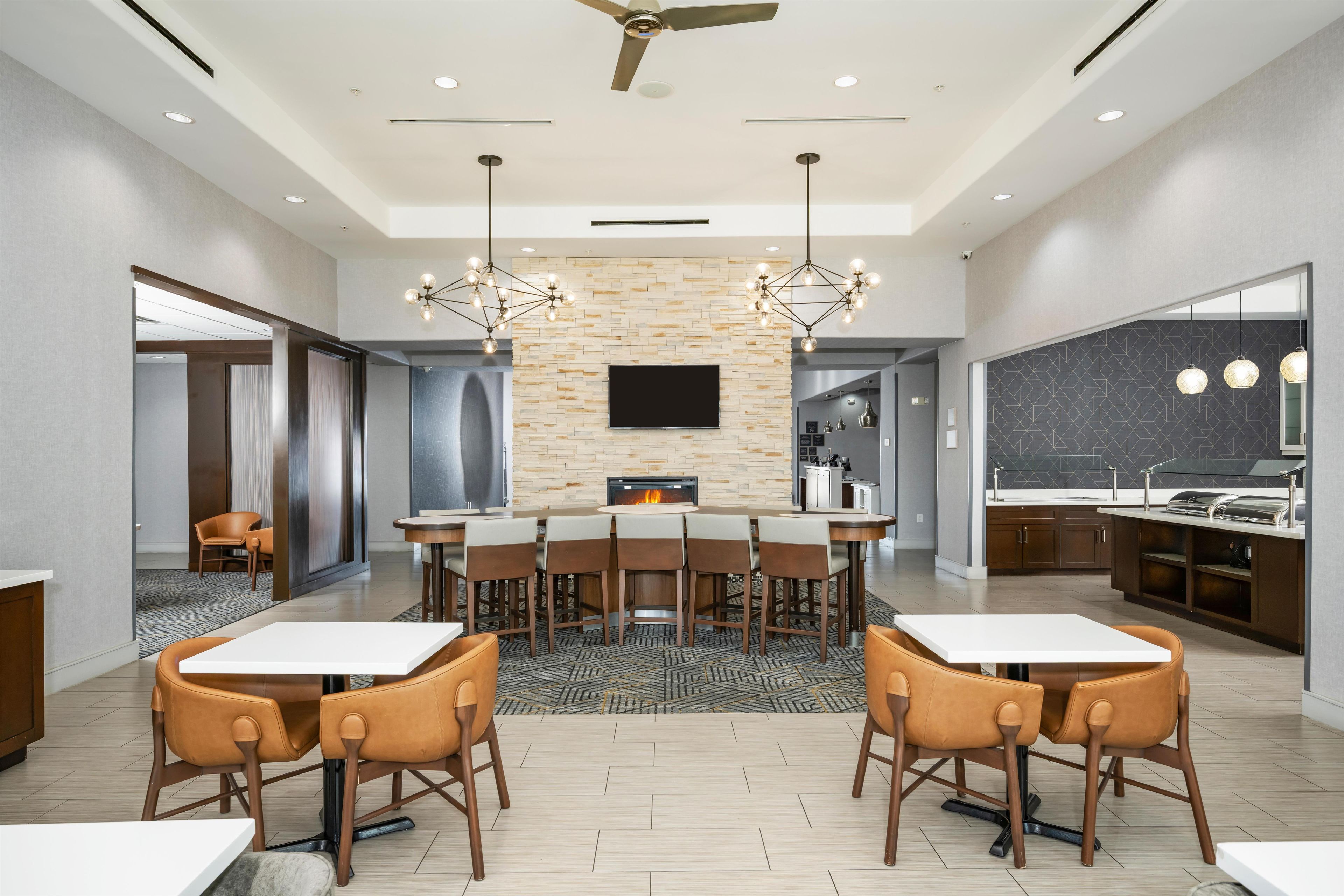 A modern dining area with a fireplace, a flat-screen TV, and a kitchen area with a grill.
