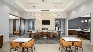 A modern dining area with a fireplace, a flat-screen TV, and a kitchen area with a grill.