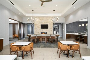 Un espace repas moderne doté d’une cheminée, d’un téléviseur à écran plat et d’un coin cuisine avec un barbecue.