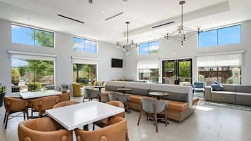 A spacious indoor area with a seating arrangement, a dining table, and a large window providing a view of the outdoors.