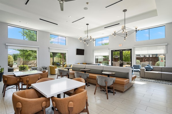 A spacious indoor area with a seating arrangement, a dining table, and a large window providing a view of the outdoors.