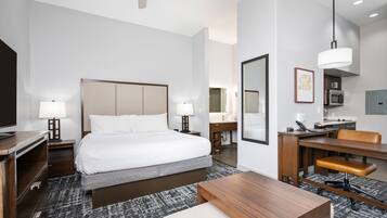 Una habitación de hotel con cama, escritorio, silla, lámpara y un espejo grande.