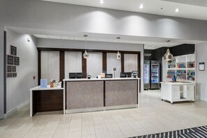 A hotel reception area with a reception desk, a shop, and a self-service kiosk. - Homewood Suites By Hilton New Braunfels (New Braunfels)