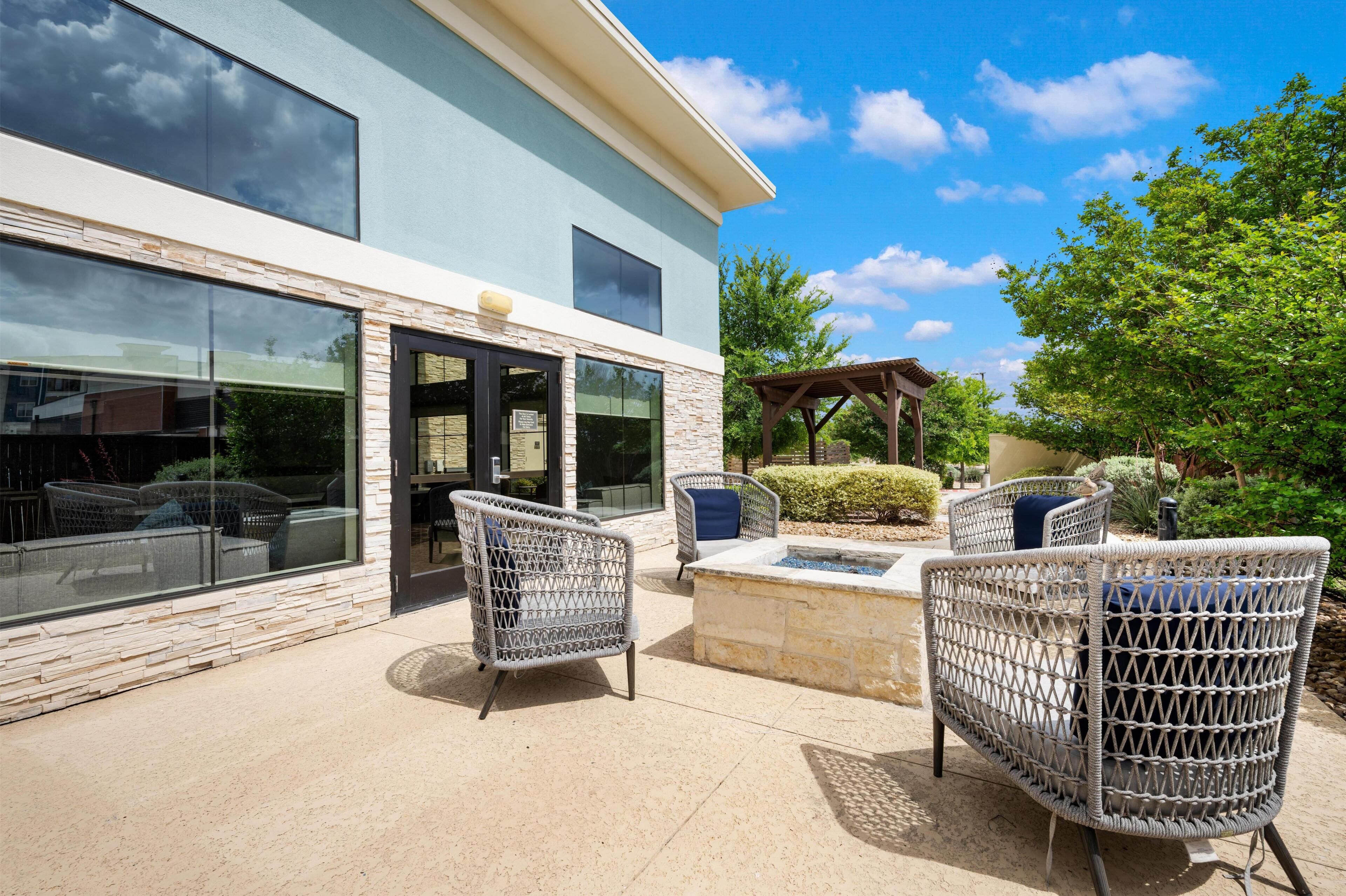A building with a stone facade, large windows, and outdoor wicker furniture.