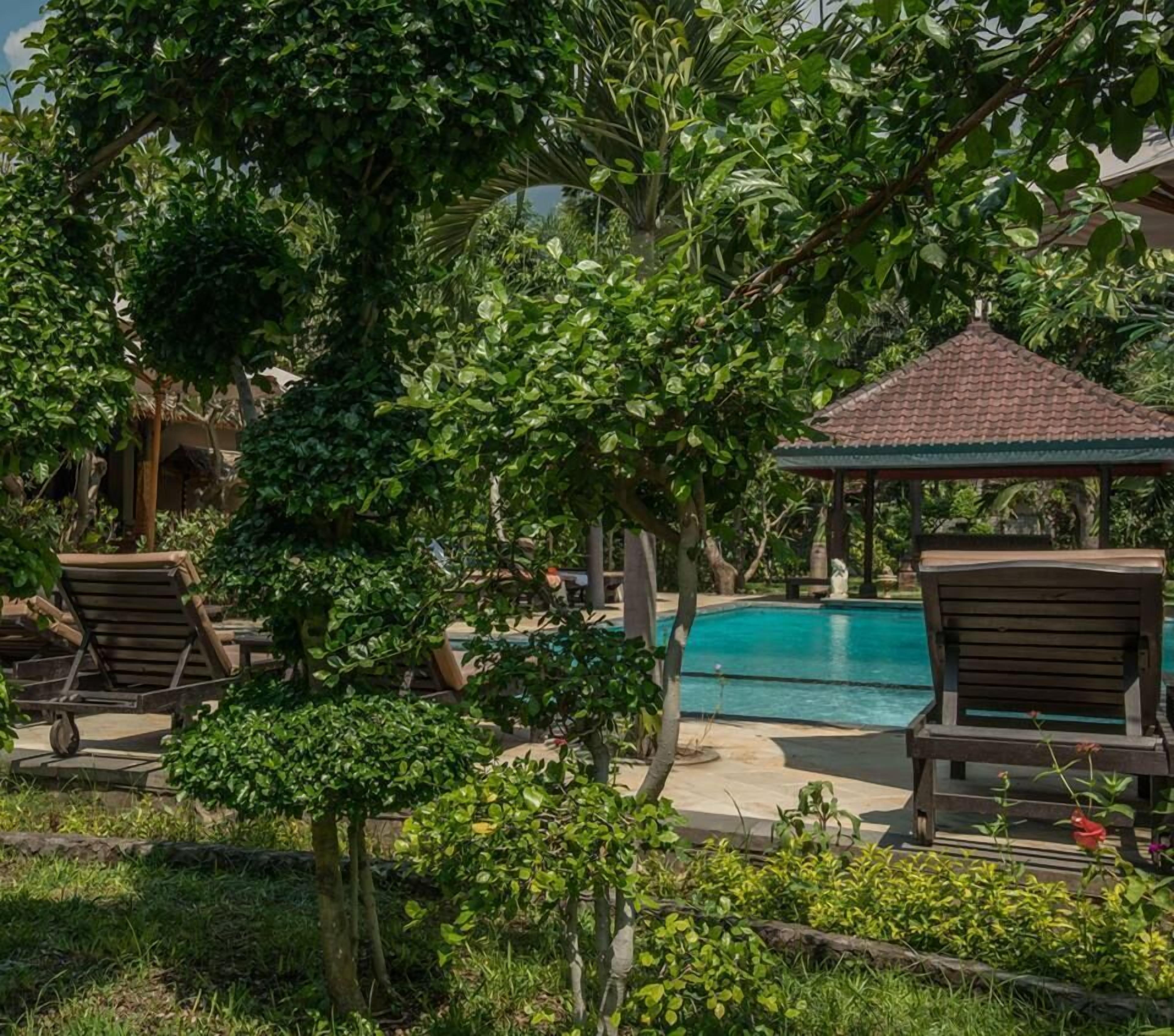 A pool area with lounge chairs and a gazebo.