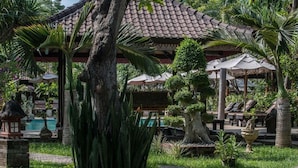 A tropical resort with a pool, covered seating areas, and lush greenery. - Tirta Sari Bungalows & Spa (Pemuteran)