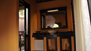 A bathroom with a sink, mirror, and cabinets. - Tirta Sari Bungalows & Spa (Pemuteran)
