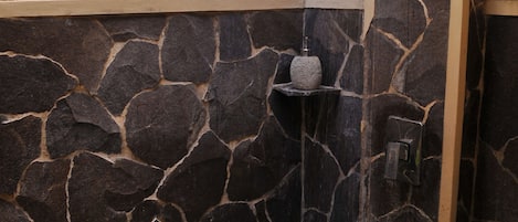 A stone shower enclosure with a built-in shelf and a showerhead.