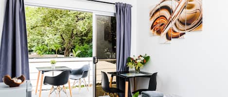 Une chambre moderne dotée d’une grande porte-fenêtre coulissante donnant sur un balcon, d’une petite table avec des chaises et d’un lit avec des serviettes.