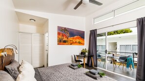 Un dormitorio moderno con una cama grande, un escritorio y un balcón con vistas.
