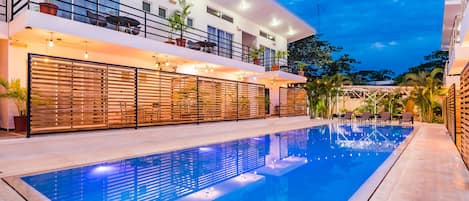Un hotel moderno con una amplia piscina cubierta, varios balcones y zonas de estar al aire libre.