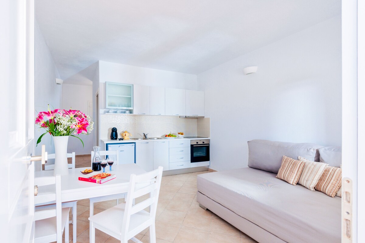 A compact living space with a dining area, kitchenette, and a sofa.