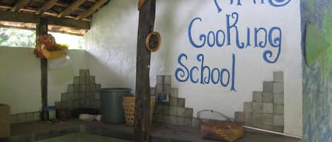 Un área de cocina rústica con un cartel que dice "ANIS Cooking School" y un salpicadero de azulejos.