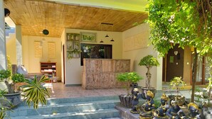 Un interior tradicional con una mesa de recepción, plantas en macetas y estatuas.